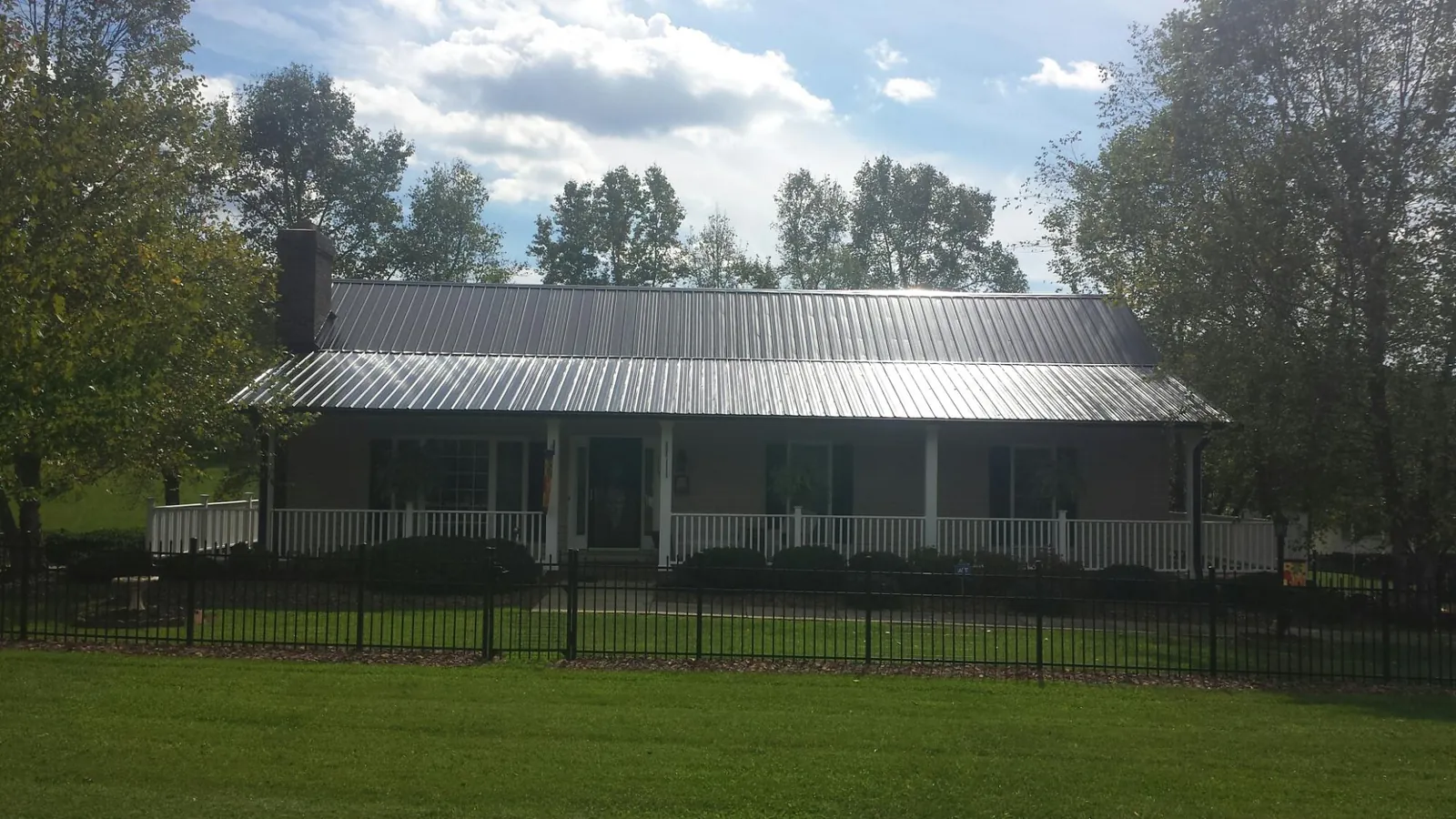 Gray metal roof on a brick ranch with a full width front porch — Gutter Guard Installation work by our crew in Adrian